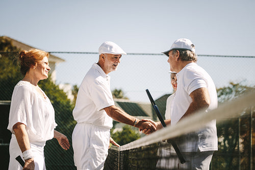 Seniors playing mixed doubles tennis game