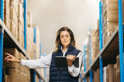 Warehouse worker looking at an inventory list on a digital tablet