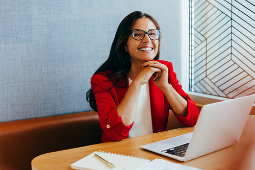 Professional woman smiling inside an office while working on her laptop