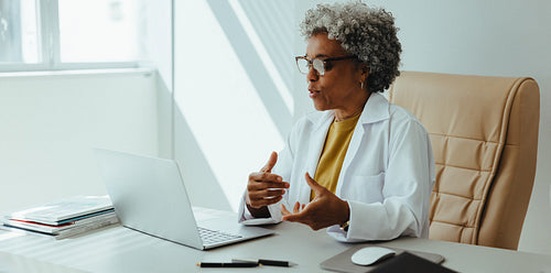 Senior female dentist speaks during an online consultation while working in her office