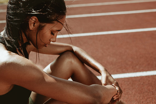 Tired runner sitting on track after training