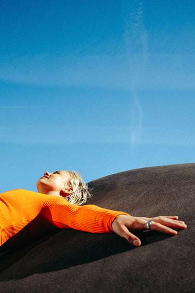 Young woman relaxes on concrete under a summer blue sky