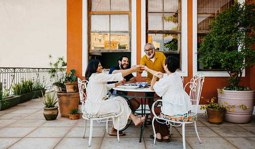 Family sharing drinks and laughter together on a sunny patio outdoors