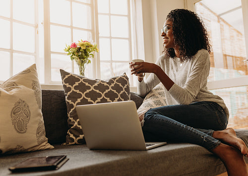 Woman enjoying a cup of coffee while working on laptop