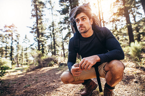 Man sitting on forest trail wearing a backpack