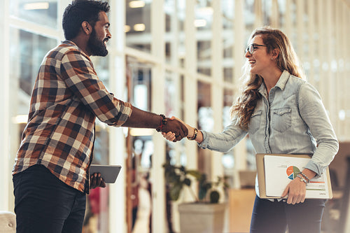 Happy business partners greeting each other at a meeting