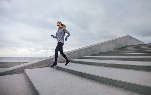 Healthy young woman running down on steps