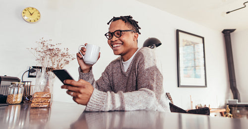 African man using phone and drinking coffee