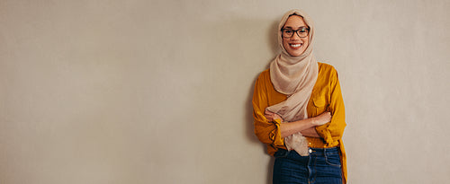 Happy muslim woman standing against a wall