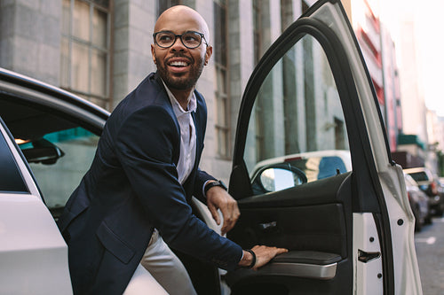 Young businessman getting down from car