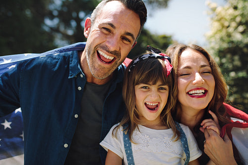 Happy family standing together holding the american flag
