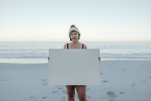 Confident winter bather holding a placard at the beach