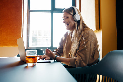 Woman wearing headphones smiling while engaging in a video call at a desk
