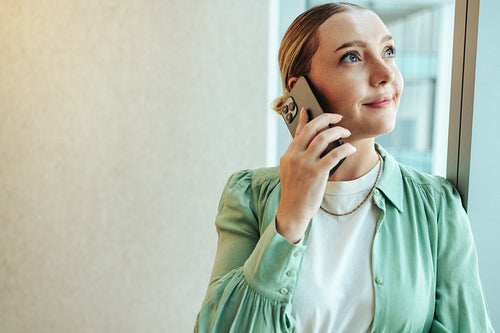 Woman smiling while talking on smartphone by office window