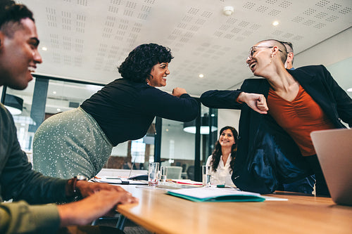 Smiling businesswomen elbow bumping each other before a meeting