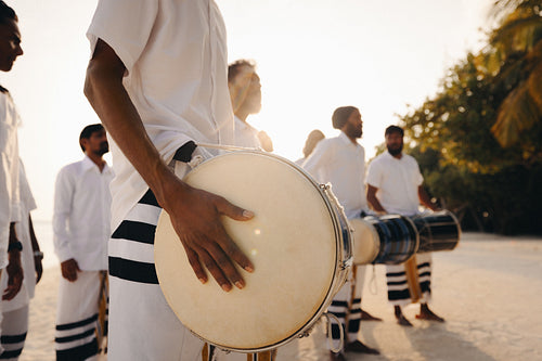 Traditional Maldivian drummers performing on tropical beach at sunset