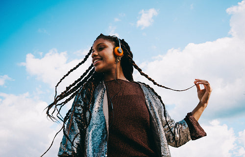 Music lover with headphones, woman listening under a blue sky