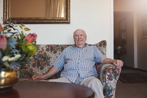 Happy senior man sitting relaxed on a couch 