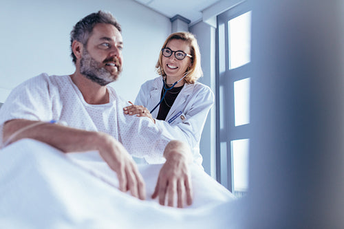 Female doctor checking male patient in hospital room