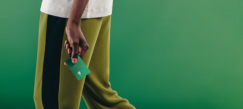 Eco-friendly consumerism: Man walking with a green credit card in his hand