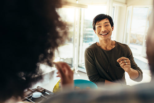 Asian man sitting at beach house with friends
