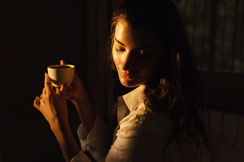 Gorgeous young woman enjoying coffee in a hotel room