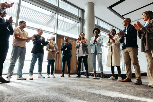 Multiethnic business team clapping in meeting room during motivational team building session