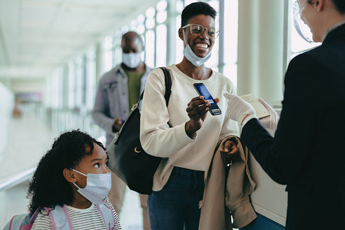 Traveling family showing digital boarding pass to attendant