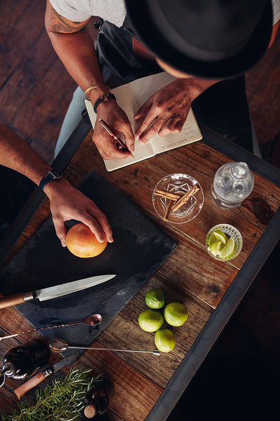 Bartenders experimenting with creating cocktails and taking down notes