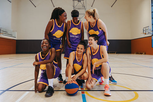 Group of female basketball players celebrating victory in an indoor court