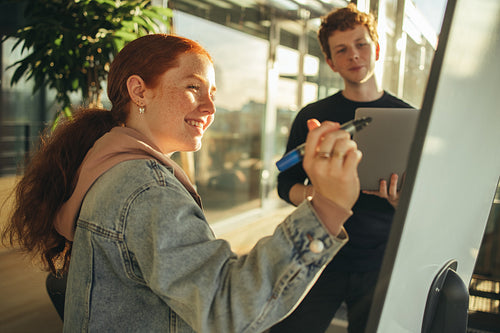 Student writing on whiteboard in classroom