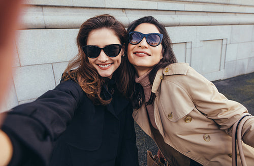 Female friends making a self portrait in the city
