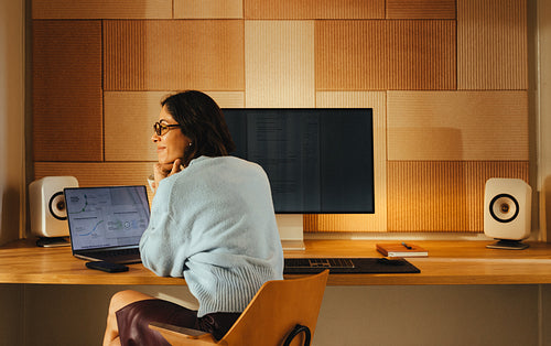 Thoughtful woman sits at her laptop at her office desk