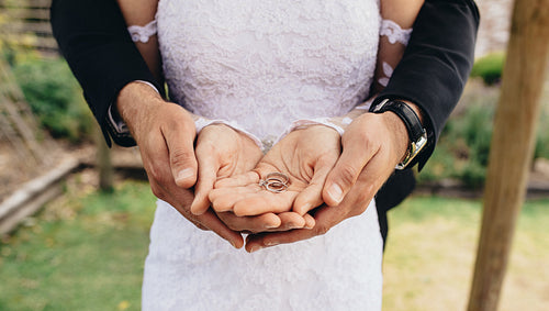 Wedding rings in hands of groom and bride
