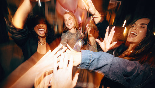 Group of friends cheering and celebrating at a lively nighttime gathering