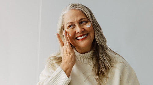 Mature woman applies face cream for skincare routine