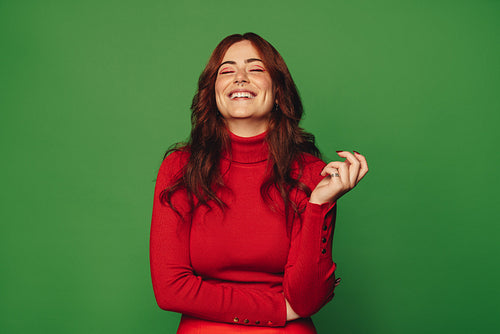 Cheerful young woman with trendy style standing on vibrant green background