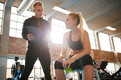 Young woman discussing exercise plan with her personal trainer
