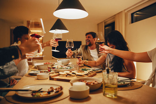 Friends enjoying dinner and wine together in a warm indoor scene