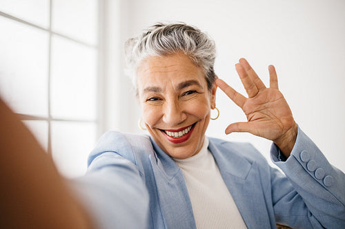 Senior business woman smiling and waving on a video call
