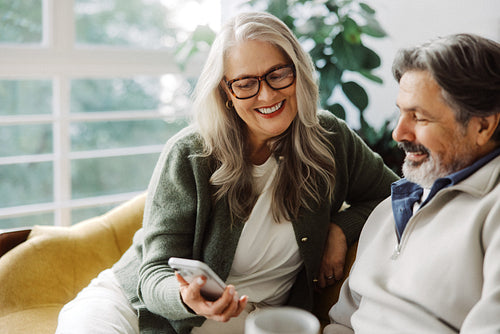 Senior couple browse online content on a smartphone at home