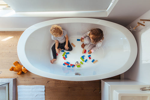 Siblings playing inside a bathtub