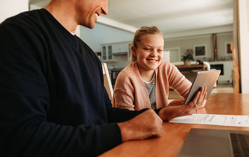 Father and daughter using digital tablet at home