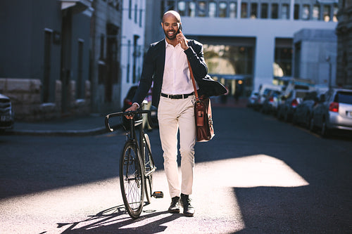 Businessman going to office with bicycle using phone