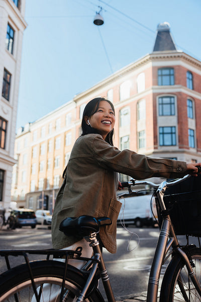 Smiling woman with bicycle in sunny city street