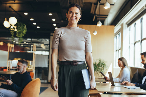Happy businesswoman standing in a co-working space
