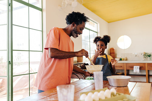 Family baking at home: Dad and daughter mixing ingredients in the kitchen