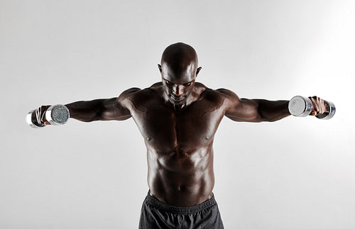 African man doing arms exercise with dumbbells