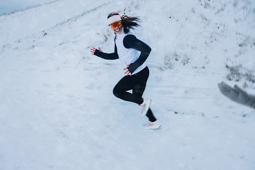 Solo running shows the woman moving through winter snow on a hill trail