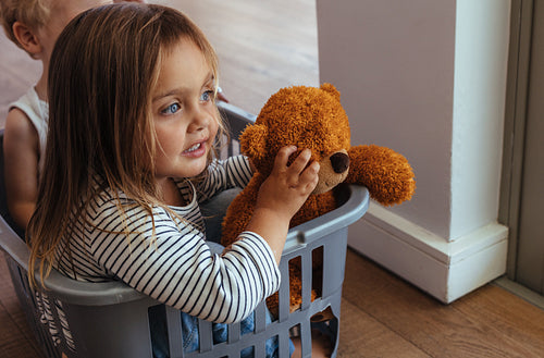 Siblings playing in a washing basket at home
